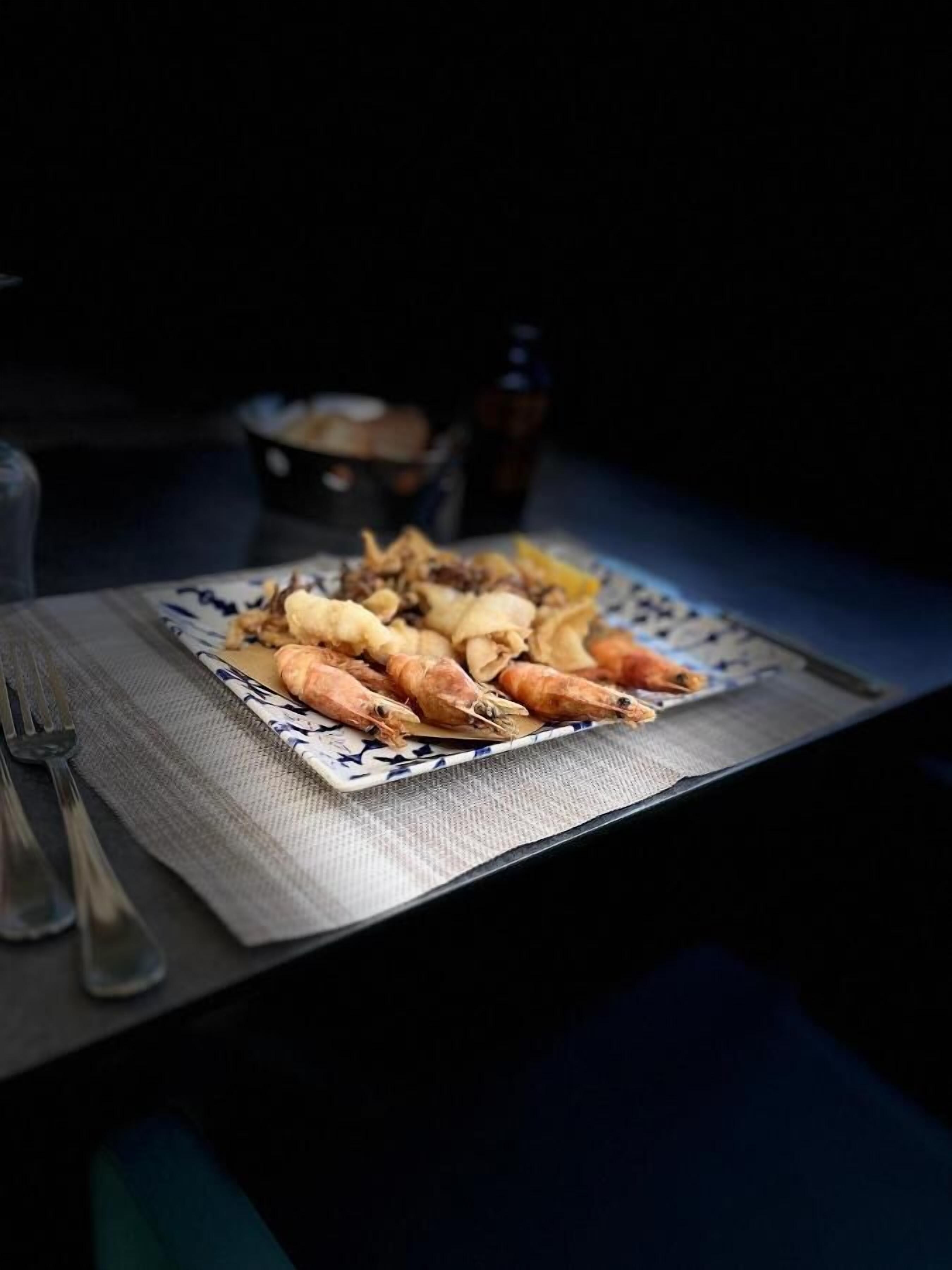 Een bord eten op een tafel, met een fles op de achtergrond.
