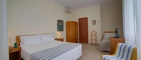 Una habitación de hotel con una cama grande, una silla, un escritorio, un armario y un televisor.