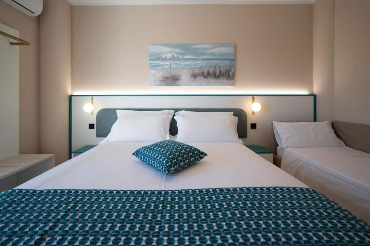 Une chambre d’hôtel avec un grand lit, deux tables de chevet, une petite table et un tableau au mur.