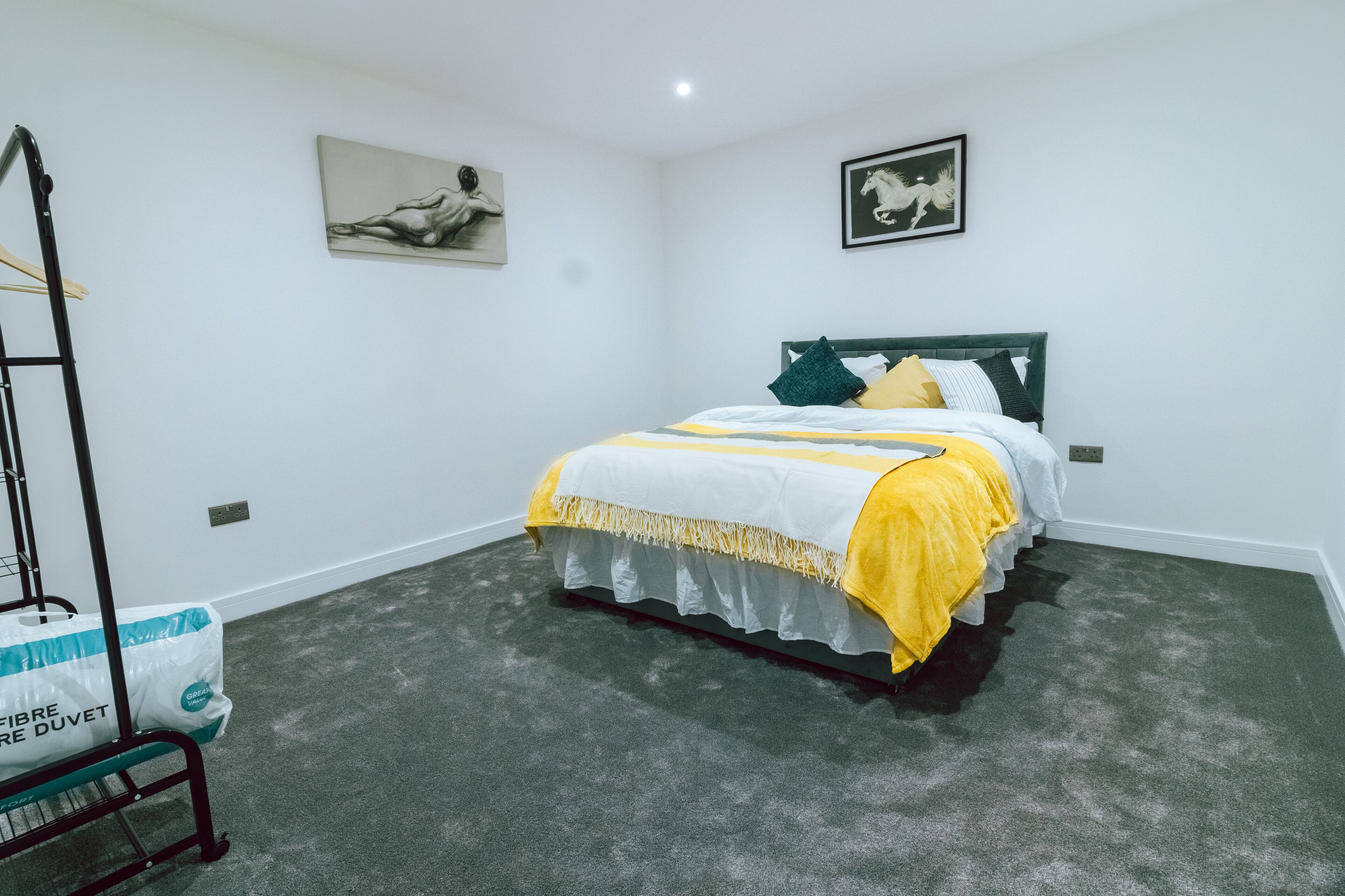 Een slaapkamer met een bed, een ladder en een zak schoonmaakspullen.