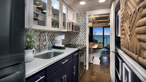A modern kitchen with a large island, stainless steel appliances, and a view to the outside.