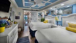 A bedroom with two beds, a ceiling fan, a mirror, and a view of the hallway.