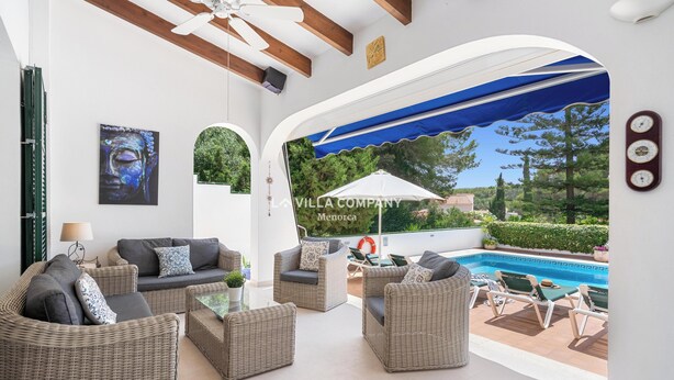 Un vaste patio aménagé avec des meubles en osier, une piscine et une vue sur la verdure.