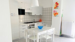 A modern kitchen with white cabinets, a gas stove, and a dining table with chairs. - I FIORI DI DONNA ESTER (Pisciotta)