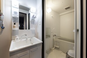 A modern bathroom with a white sink, mirror, and shower. - STELLAR 605 (Sapporo)
