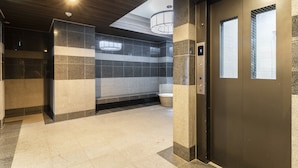 Un baño moderno con techo de madera oscura, paredes con azulejos y un inodoro a la vista.