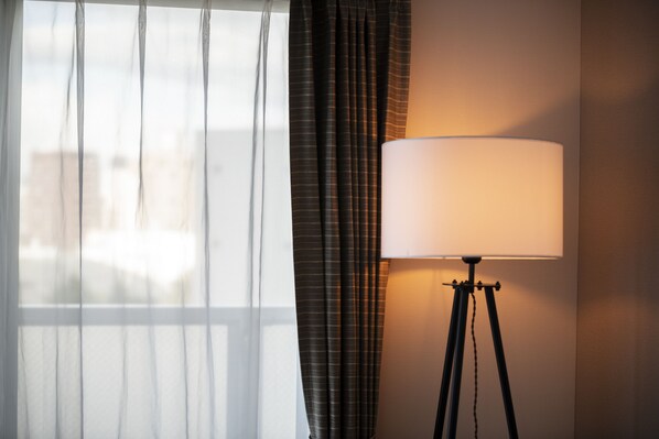 A lamp on a tripod stand next to a window with sheer curtains. - STELLAR 605 (Sapporo)