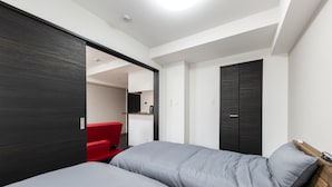 Un dormitorio moderno con dos camas, una silla roja y un armario.
