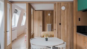 A room with a round table, a radiator, and wooden paneling. - Top-Floor Soho Flat | AC | Sleeps 4 | Central Ldn (Greater London)