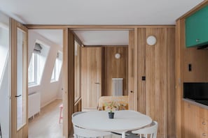 A room with a round table, a radiator, and wooden paneling. - Top-Floor Soho Flat | AC | Sleeps 4 | Central Ldn (Greater London)