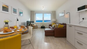 Een moderne woonkamer met een eetgedeelte, een bank en uitzicht op zee.