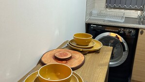 Eine Küche mit Waschmaschine, Holzschneidebrett und gelben Schüsseln auf der Arbeitsplatte.