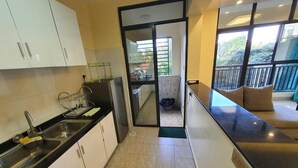 Une cuisine moderne avec des meubles blancs, un plan de travail noir et une vue sur un balcon.