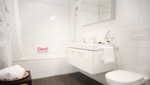 A modern bathroom with a white vanity, a toilet, and a shower area.