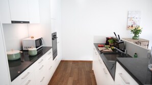 A modern kitchen with white cabinets, a black countertop, and a wooden floor.