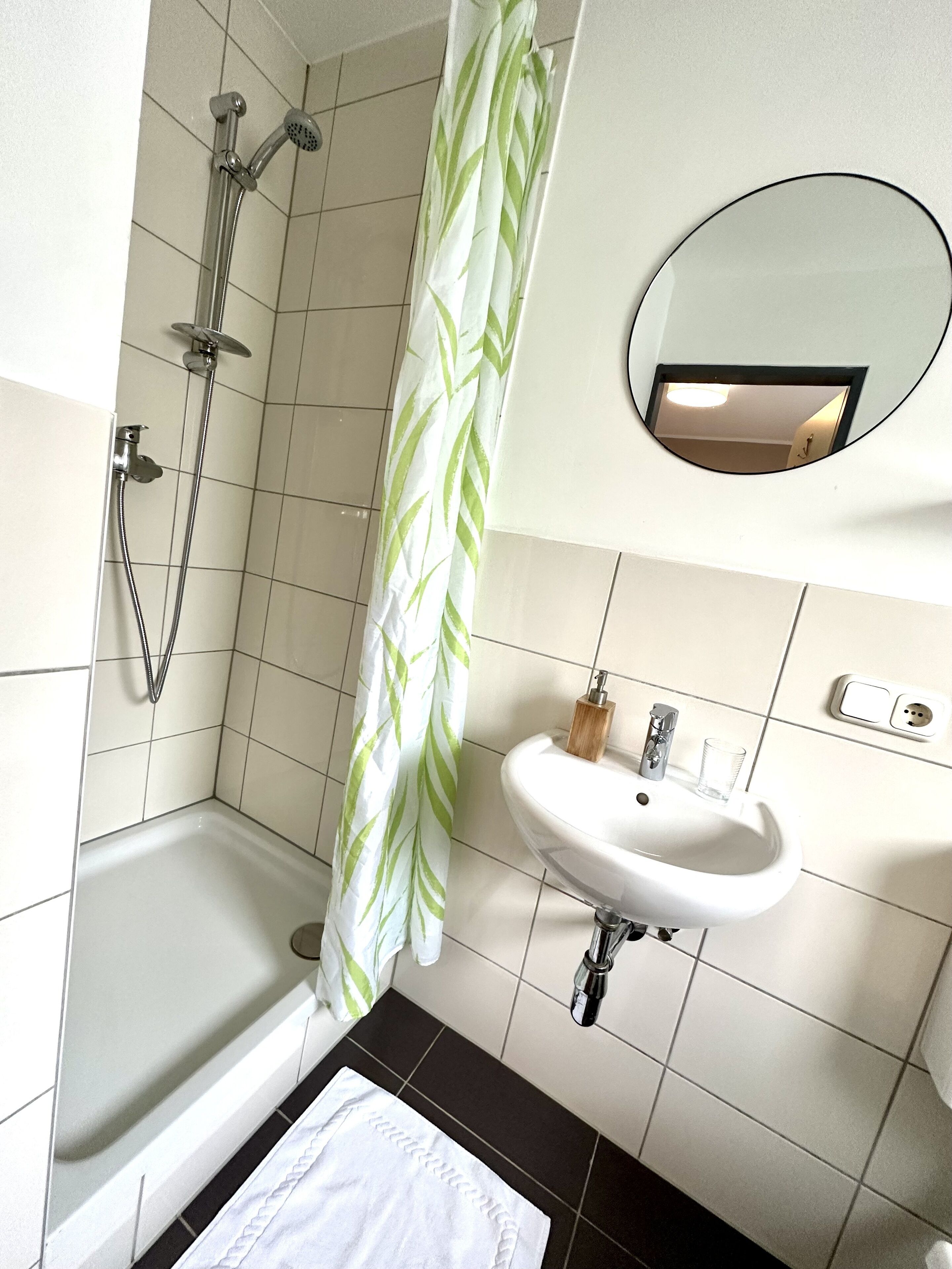A bathroom with a shower, a sink, and a mirror.