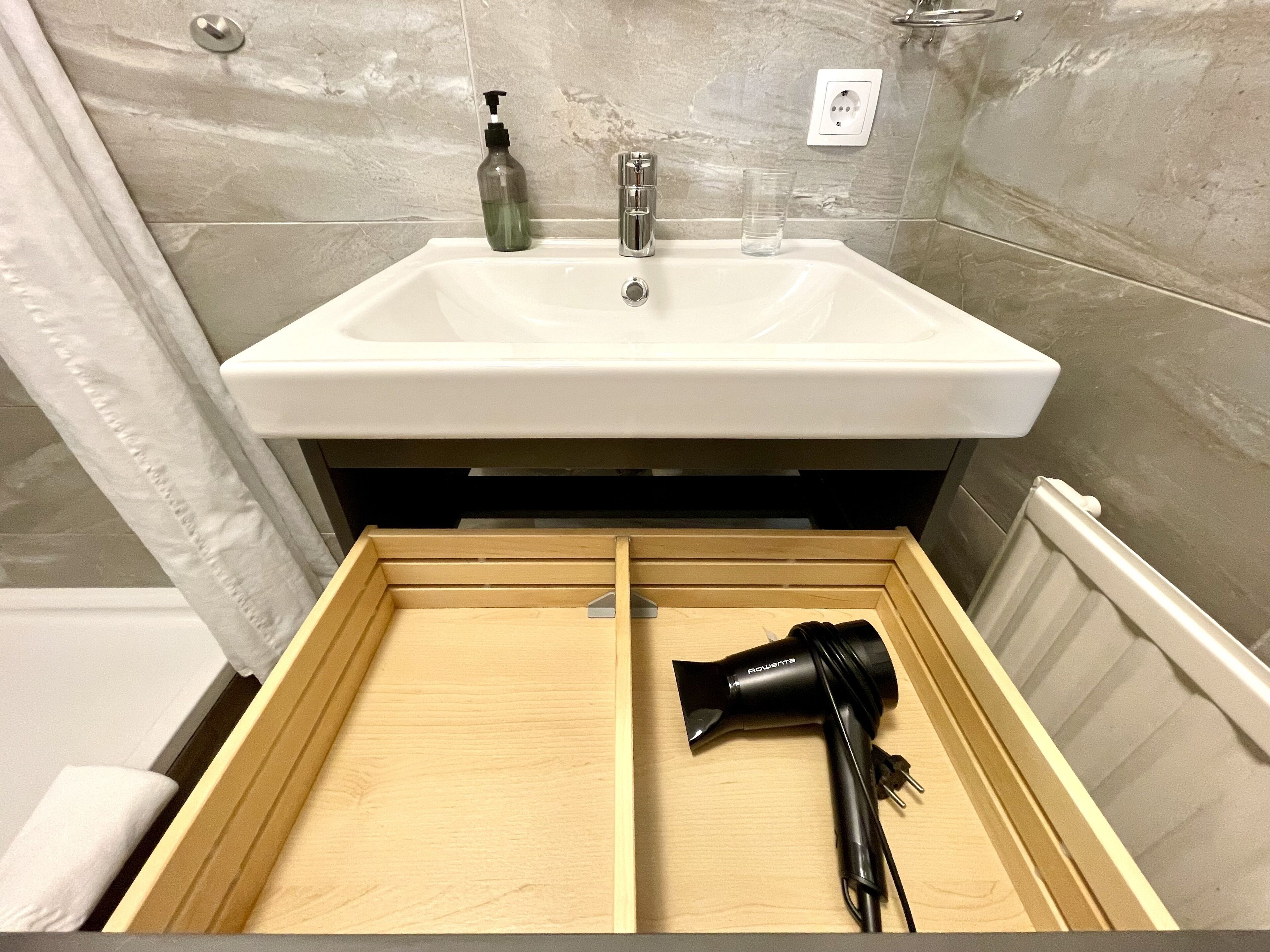 Ein Badezimmer mit Waschbecken, Spiegel und einer Holzkassette, inklusive Fön.