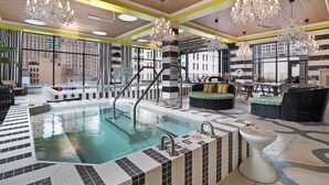 A modern indoor pool area with a checkered floor, multiple seating areas, and chandeliers. - Cincinnati City Club Apartments by Airriva (Cincinnati)
