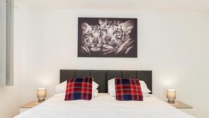A hotel room with a large bed, two nightstands, and a wall-mounted artwork of a tiger. - Innsworth House (Gloucester)