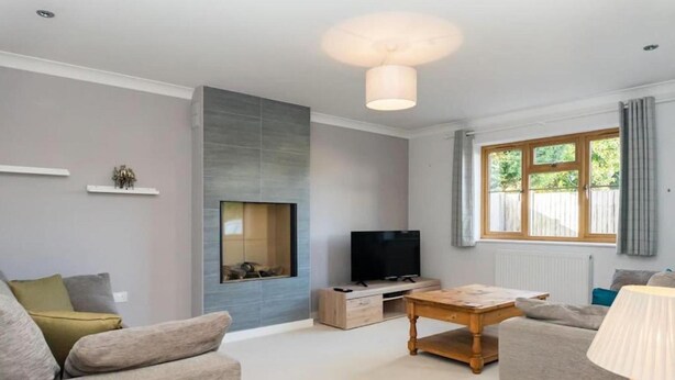 A modern living room with a flat-screen TV, a wooden coffee table, and two sofas. - Innsworth House (Gloucester)