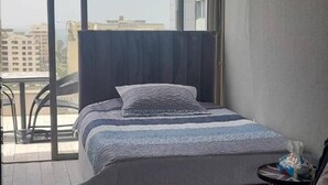 Ein modernes Hotelzimmer mit zwei Betten, einem Balkon und Blick auf die Stadt.