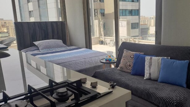 Ein modernes Hotelzimmer mit Bett, Sofa, kleinem Tisch und Blick auf die Stadt.