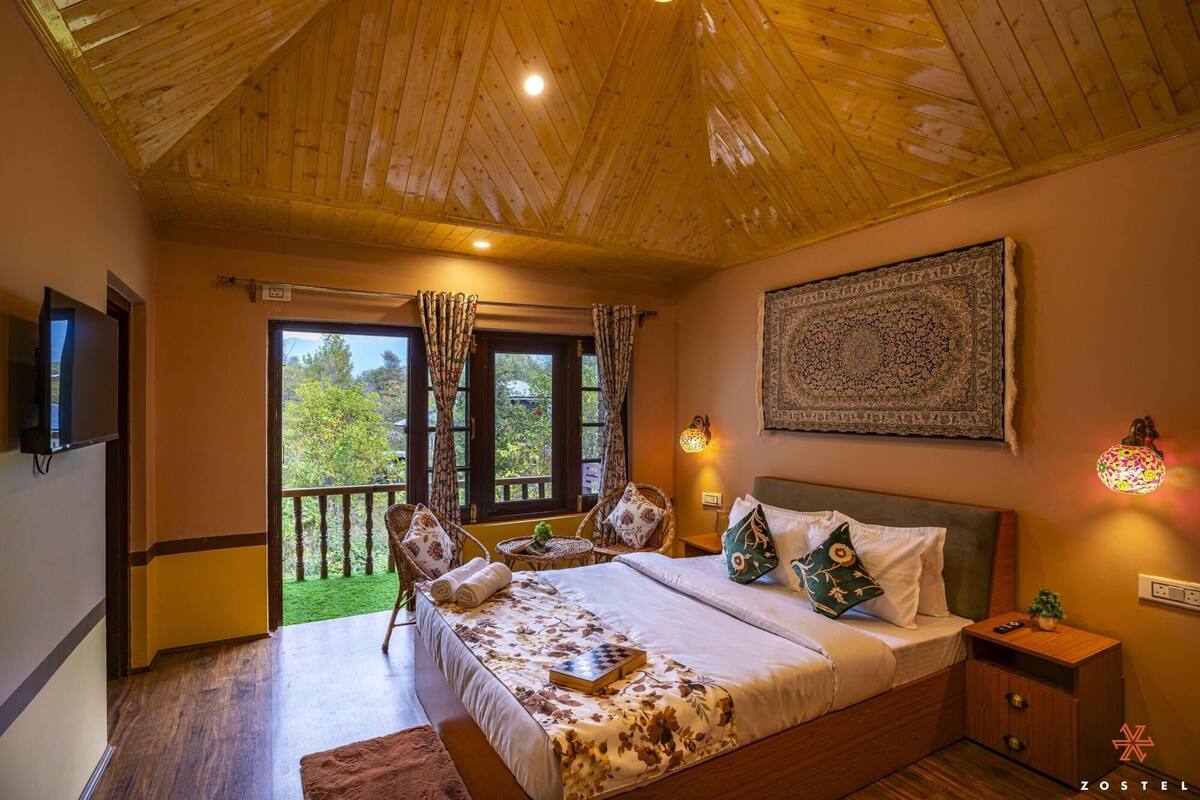 Quarto com uma cama grande, televisão, varanda e luminária fixa na parede.