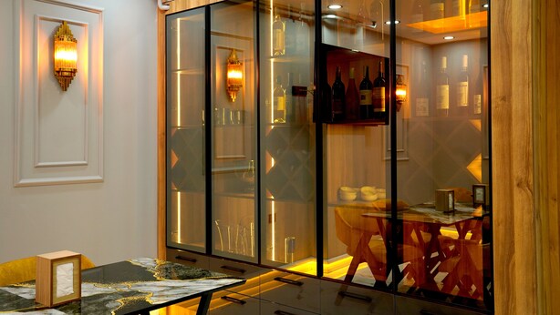 A room with a glass partition, a table with a glass top, and a wall-mounted light fixture. - Greenwich Hotel (Istanbul)