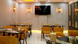 A conference room with tables and chairs, a flat-screen TV, and wall sconces. - Greenwich Hotel (Istanbul)