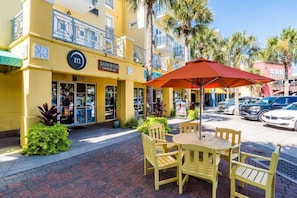 Un edificio giallo con una caffetteria chiamata Sunrise Coffee Co. e un cartello con la lettera 'm'. C'è un tavolo e delle sedie all'esterno, con un ombrellone.