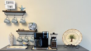 Un comptoir de cuisine avec une machine à café, une machine Keurig, un moulin à café et une assiette décorative.