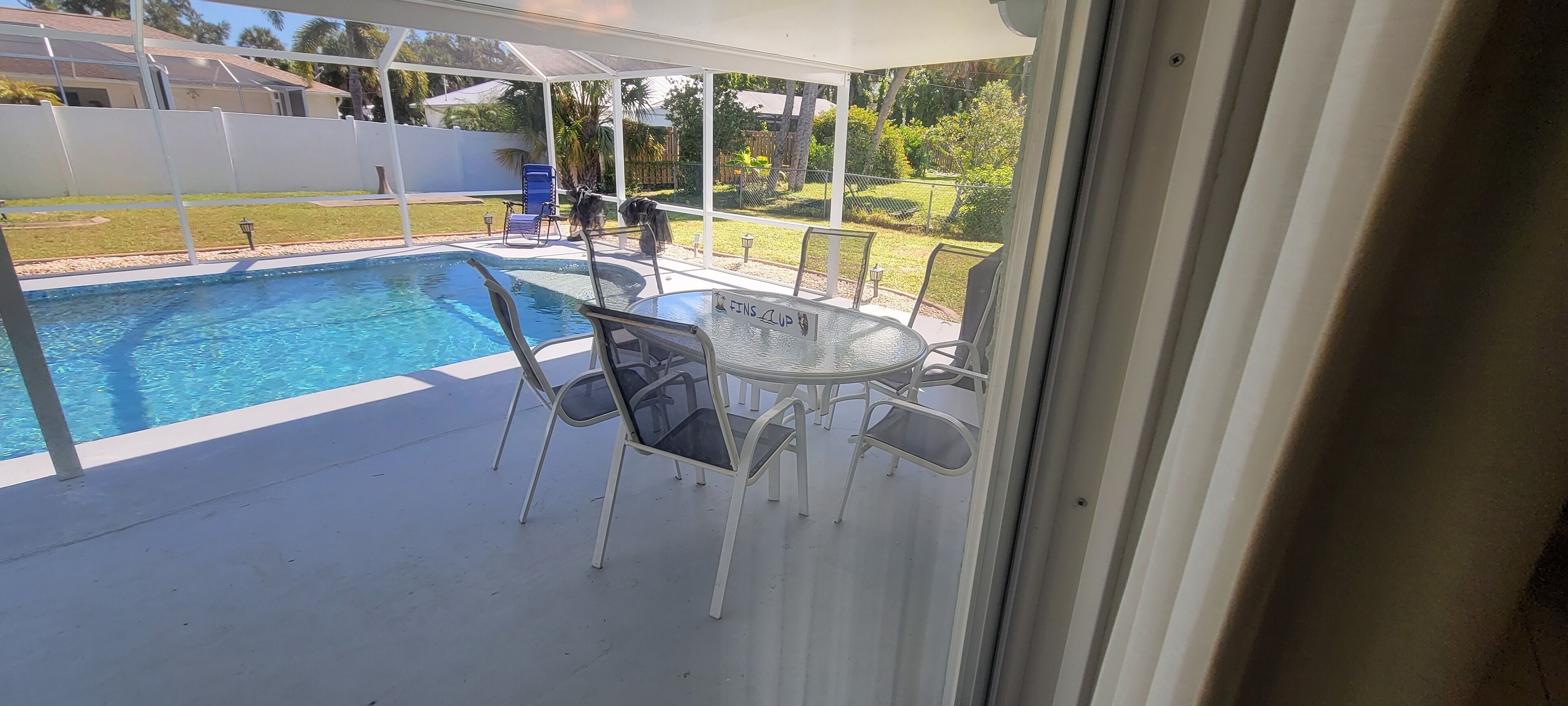 A covered outdoor area with a pool, chairs, and a table.