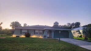 Une maison de plain-pied avec un garage, une pelouse devant et un lampadaire.