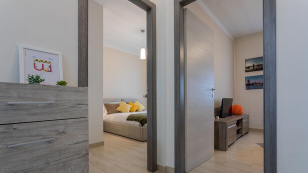 A modern living room with a sofa, a coffee table, and a TV. There is a door leading to another room. - Modern House Santa Rita by Wonderful Italy (Turin)