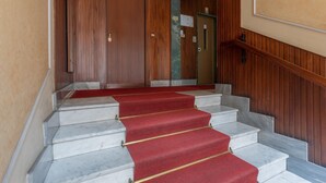 A set of marble stairs with red carpet runners, wooden paneling on the walls, and a door with a sign above it. - Modern House Santa Rita by Wonderful Italy (Turin)