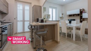 A modern kitchen with a central island, bar stools, and a dining area with white chairs. - Modern House Santa Rita by Wonderful Italy (Turin)