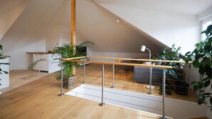 A spacious loft with a wooden floor, a balcony with a wooden railing, and potted plants. - Moderne, Helle Wohnung (Heidelberg)