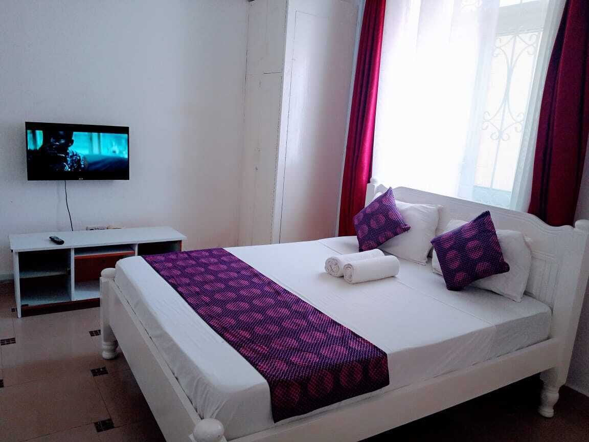Ein Hotelzimmer mit Bett, Fernseher und einem Fenster mit Vorhängen.