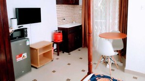 Ein kleines Hotelzimmer mit Küchenzeile, einem Flachbildfernseher, einem kleinen Esstisch und einem Bett.
