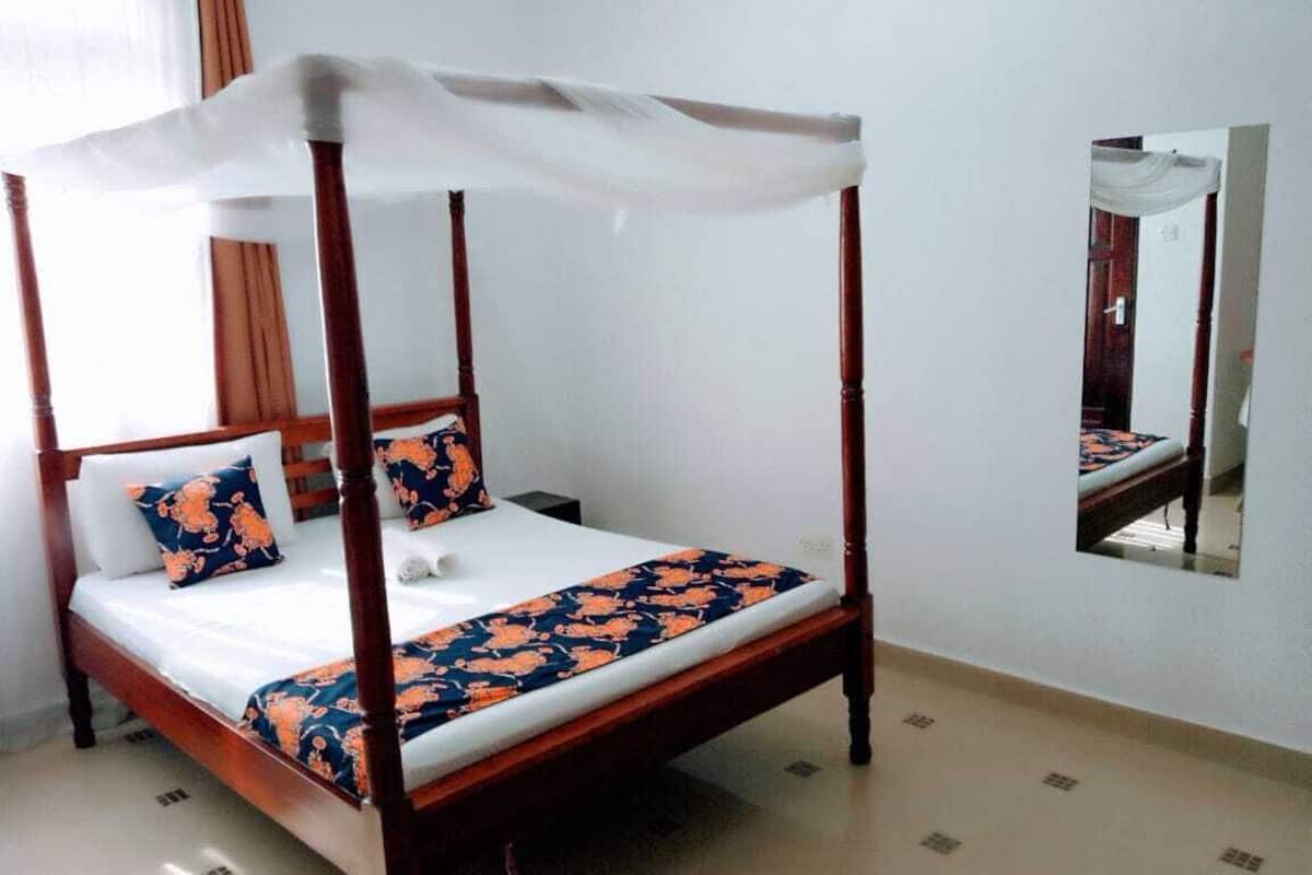 Una cama con dosel, una mesita de noche y un espejo en la pared.