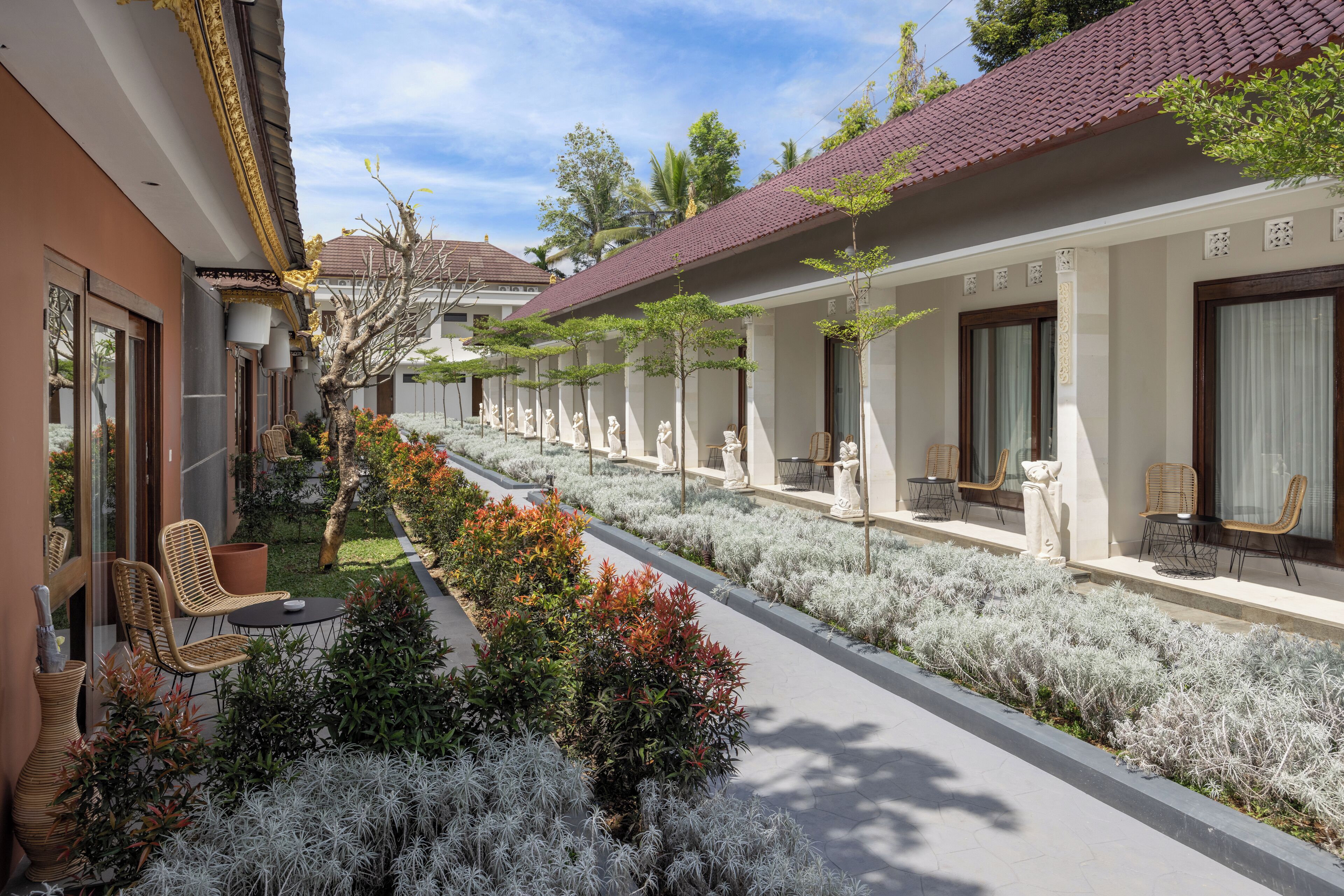 A hotel corridor with rows of rooms, each with a balcony and outdoor seating area.