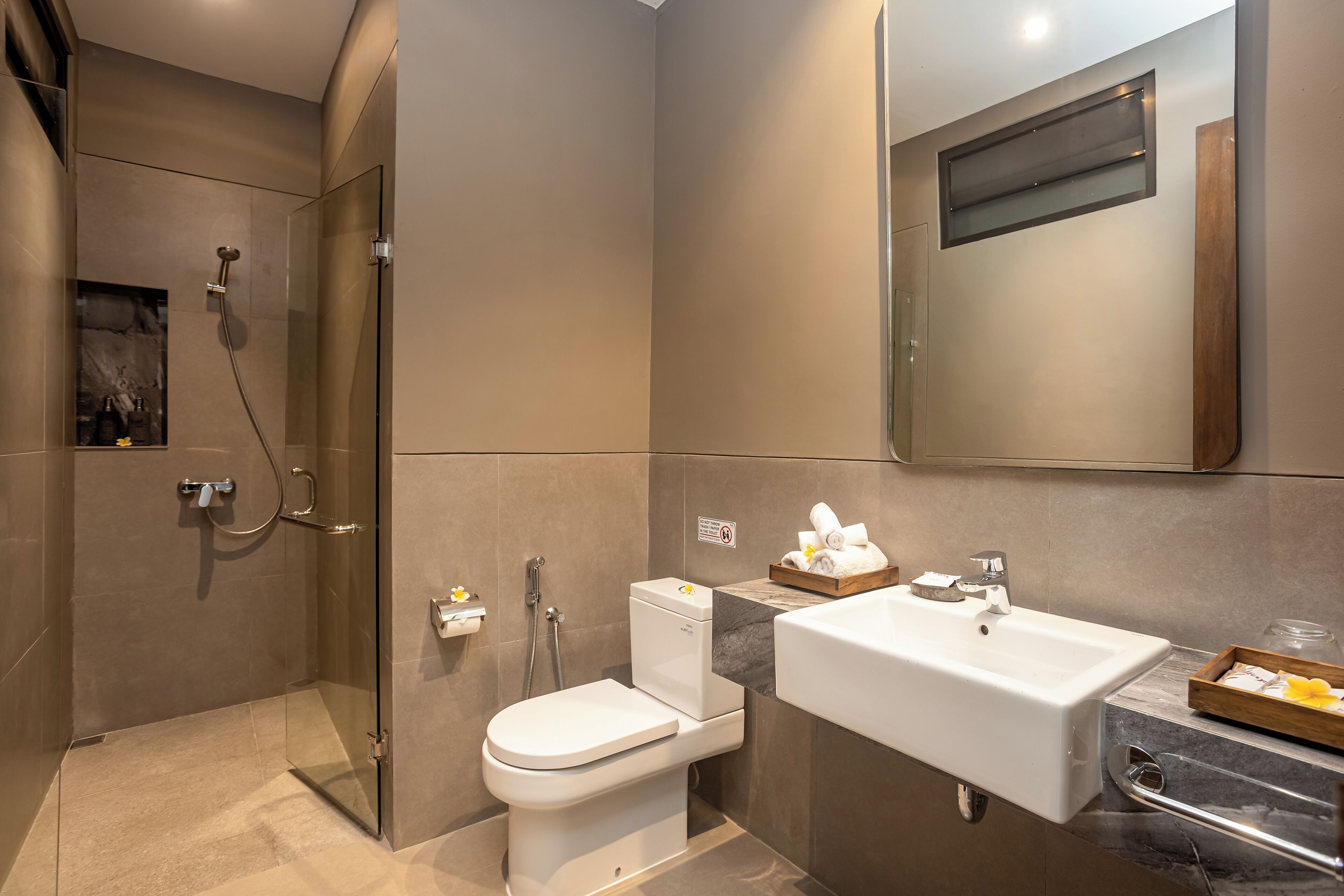 A modern bathroom with a glass-enclosed shower, a toilet, a sink with a vanity, and a mirror above the sink.