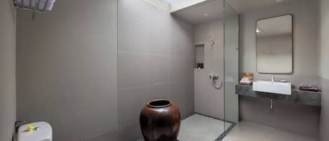 A modern bathroom with a skylight, a large vase, a toilet, and a shower area.