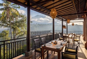 Un restaurante con terraza al aire libre y vistas a un paisaje montañoso.