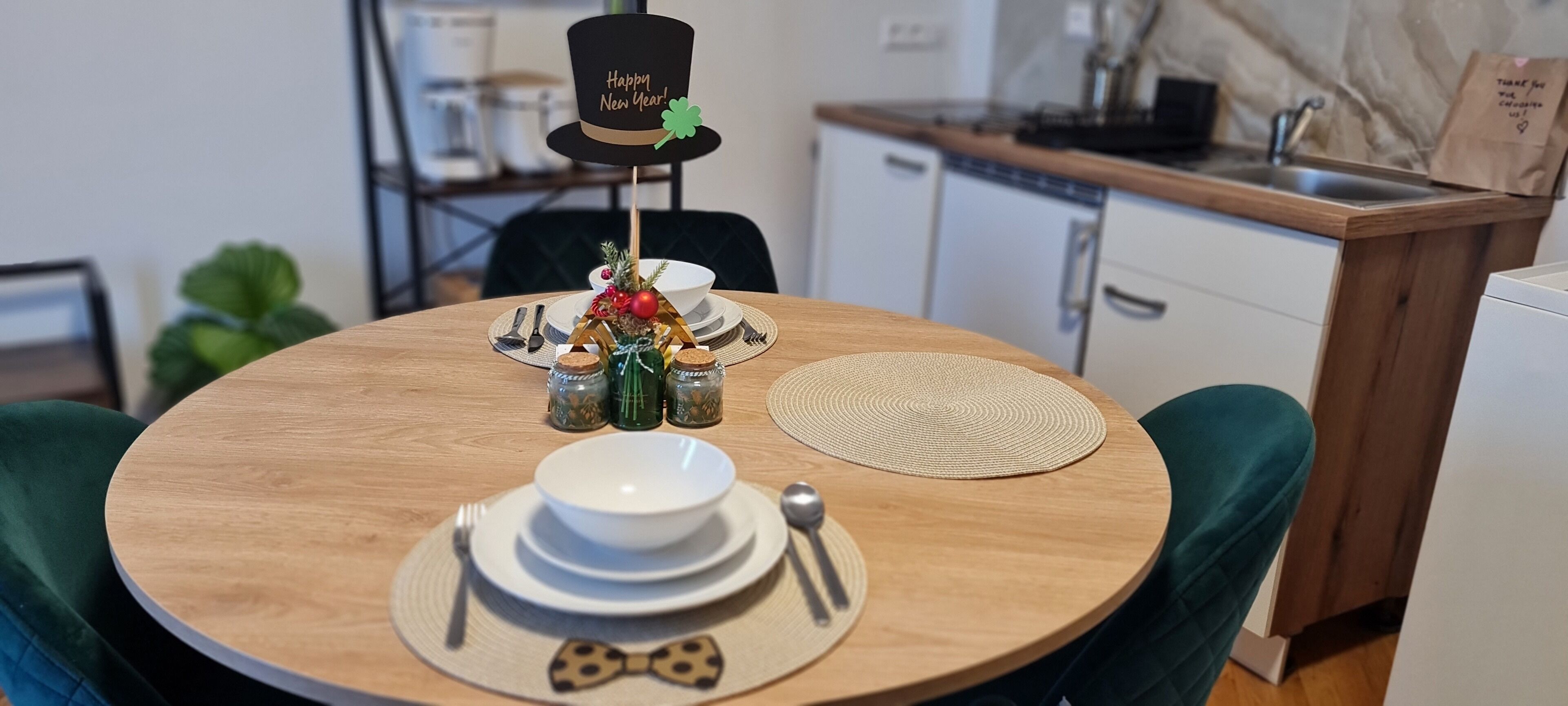 Ein runder Holztisch gedeckt mit weißen Tellern, einer Schleifenkrawatte als Serviette und einem schwarzen Zylinder mit grünem Shamrock.