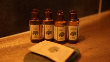 Four bottles of olive shower gel and shampoo on a wooden surface.