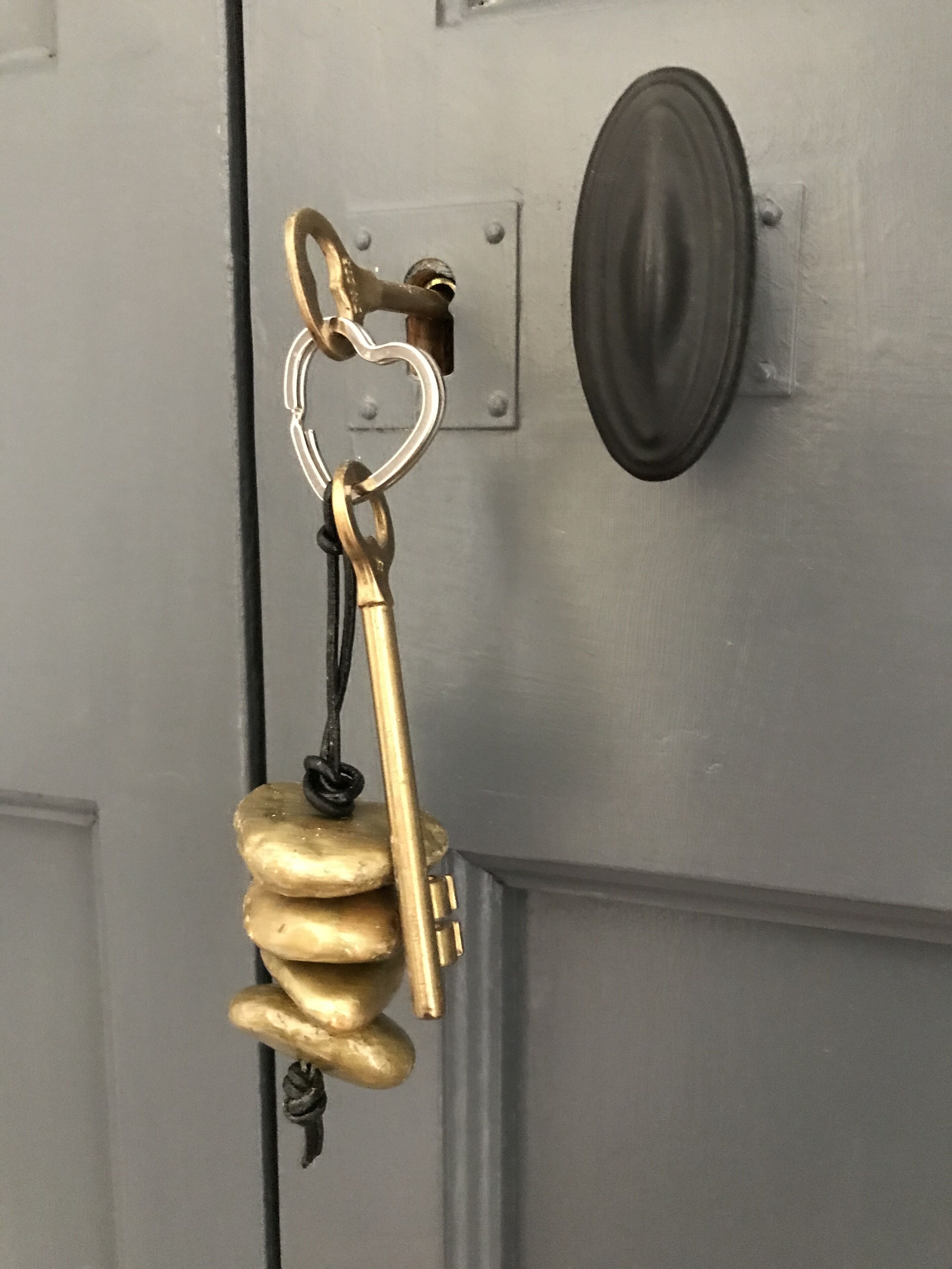 A brass keychain with a unique design, hanging on a gray door.