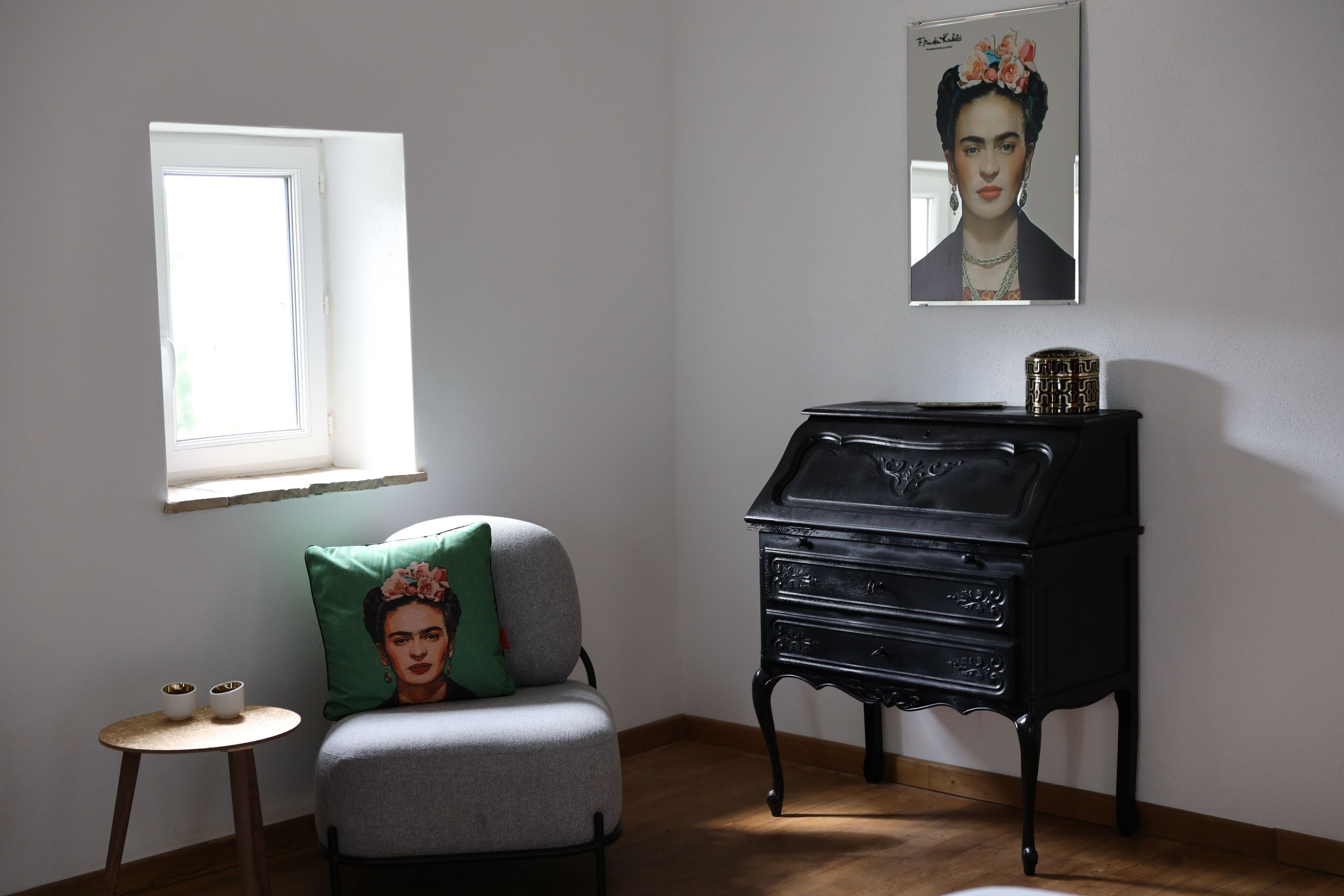 Une pièce avec un lit, une petite table sur laquelle sont posées deux tasses, une fenêtre et une commode noire.