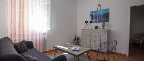 Una sala de estar con un sofá, una mesa de centro, una silla, un aparador y un cuadro en la pared.