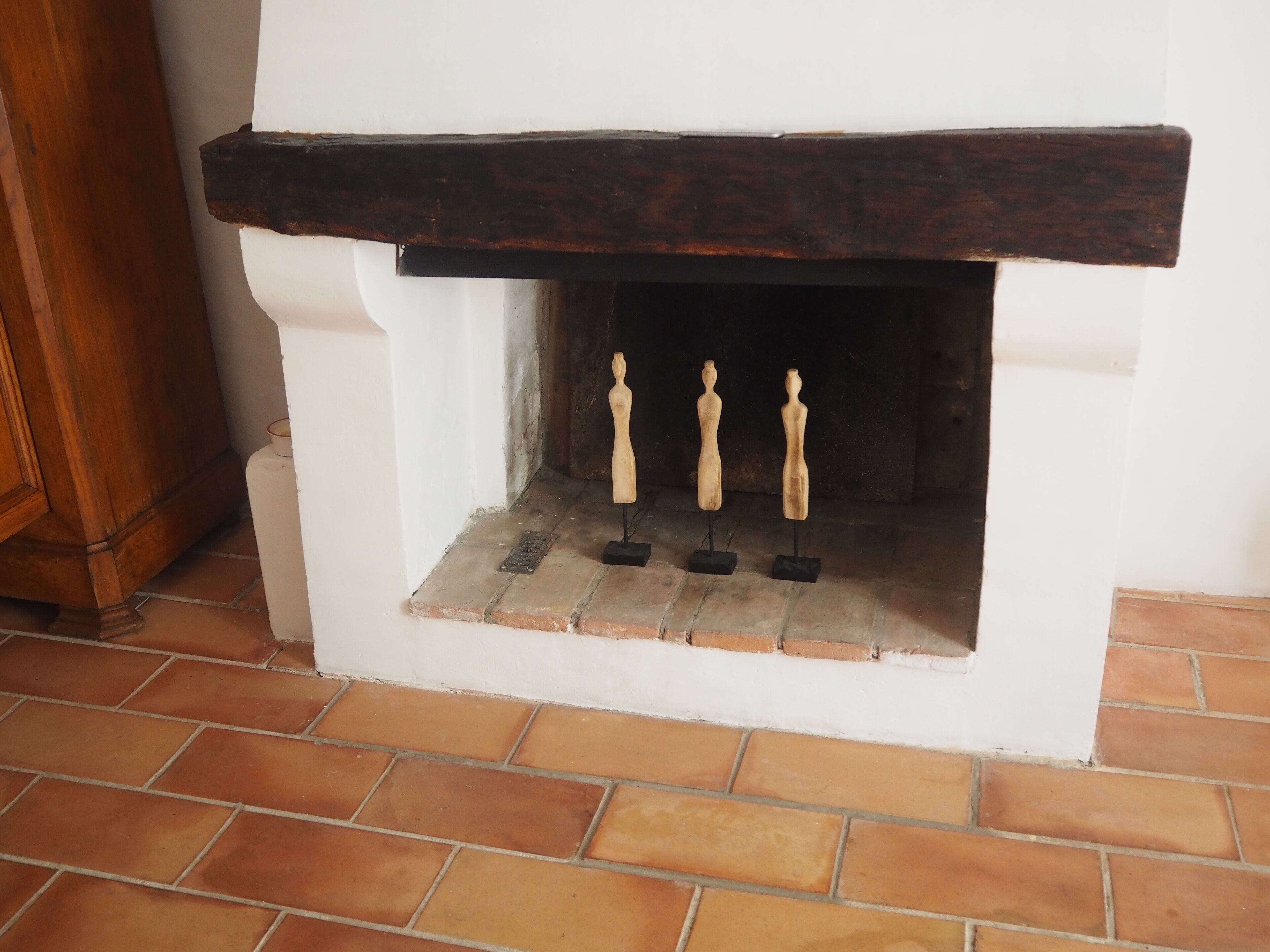 A fireplace with three wooden figurines on stands.